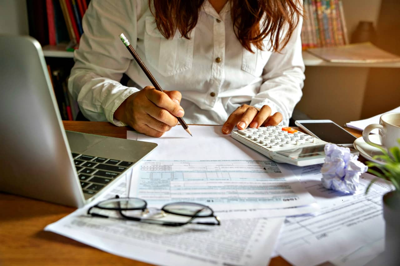 Woman working at a desk with a calculator working out a marketing budget